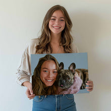 Load image into Gallery viewer, Custom art canvas wrap depicting a beautiful young woman and her Frenchie French Bulldog cuddling on a couch for a personal candid photo. The same young woman is standing and holding her custom art canvas wrap while smiling at the camera.

