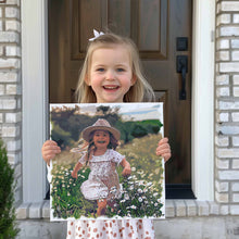 Load image into Gallery viewer, Custom art canvas wrap depicting a cute girl running through flowers. The canvas wrap is held by the same girl wearing the same dress as in the original photo and she is very happy to show off her custom canvas wrap of the picture of her

